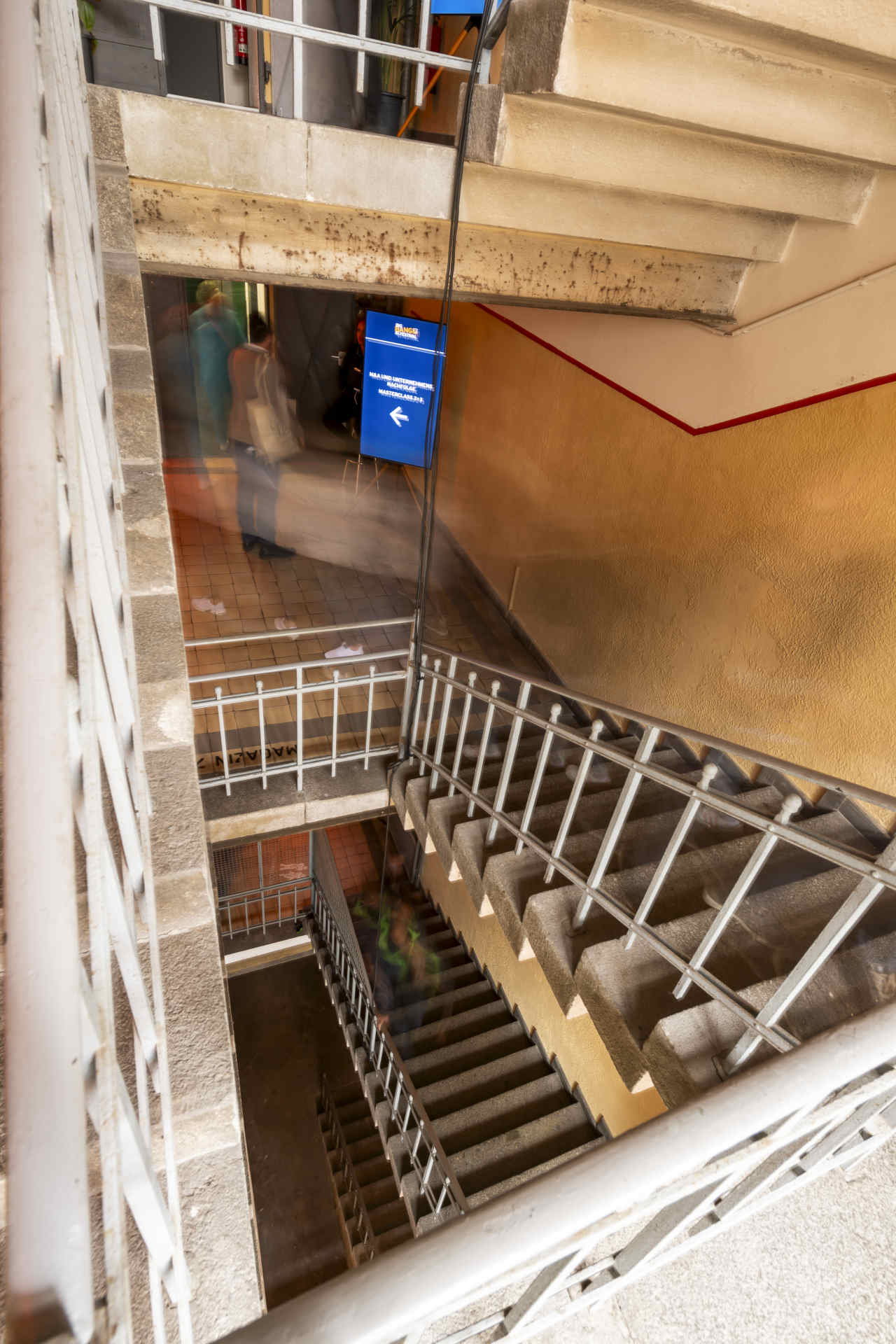 Blick in ein Treppenhaus mit Blick nach unten, die Treppen laufen im Karree herunter