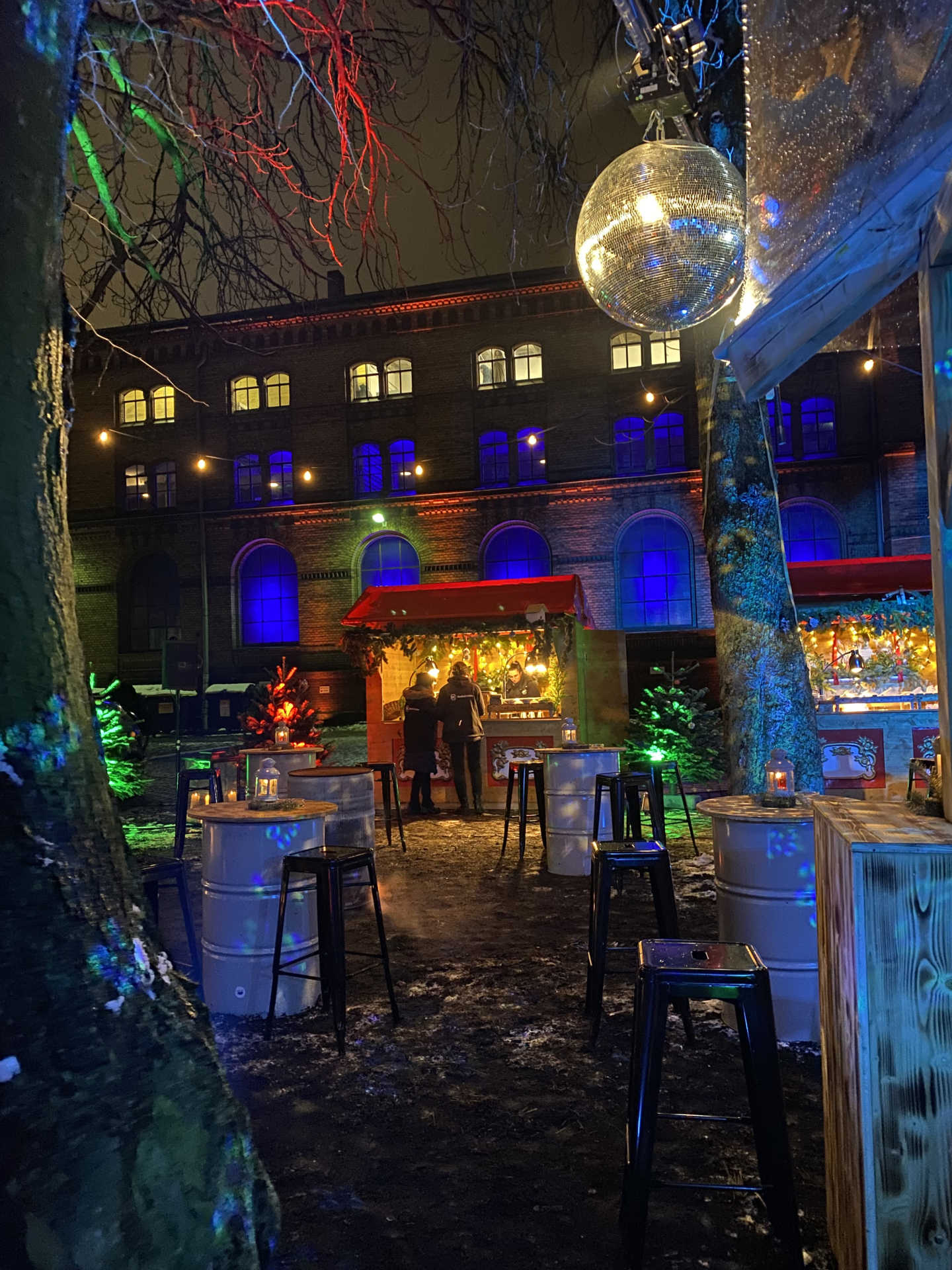 Außenbereich mit Weihnachtsbuden, Discokugel und Tonnen im Dunkeln